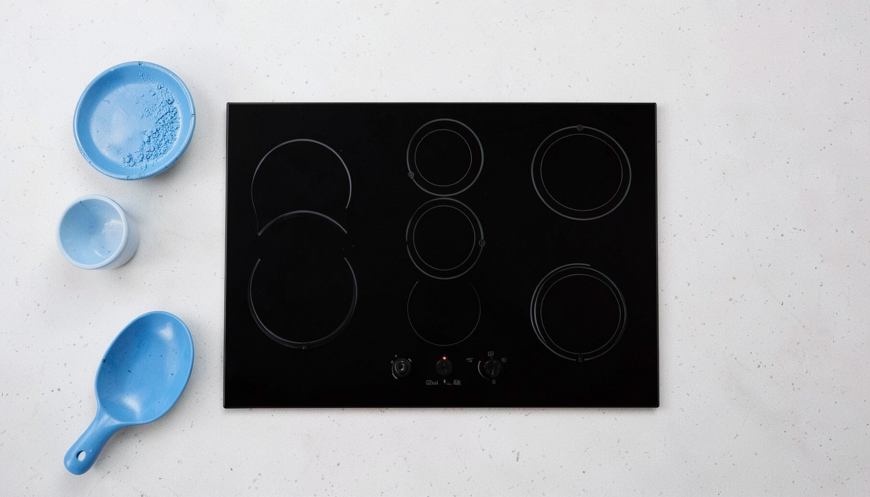 Plaque de cuisson encastrable en vitrocéramique noire avec trois foyers, installée à fleur d'un plan de travail en quartz clair